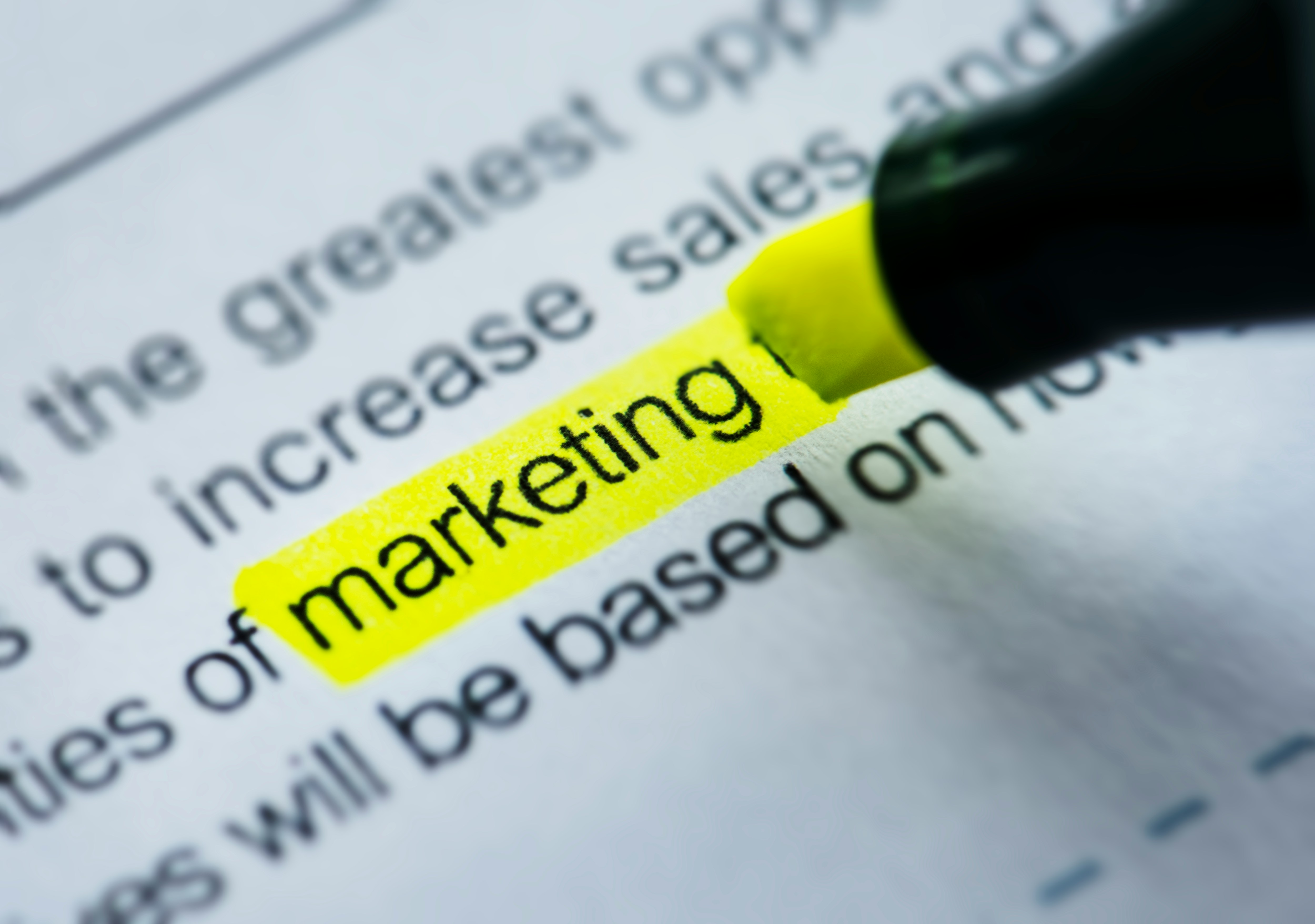 Close-up of the word “marketing” highlighted in yellow on a printed document, symbolizing focus on marketing strategy, content planning, or campaign analysis