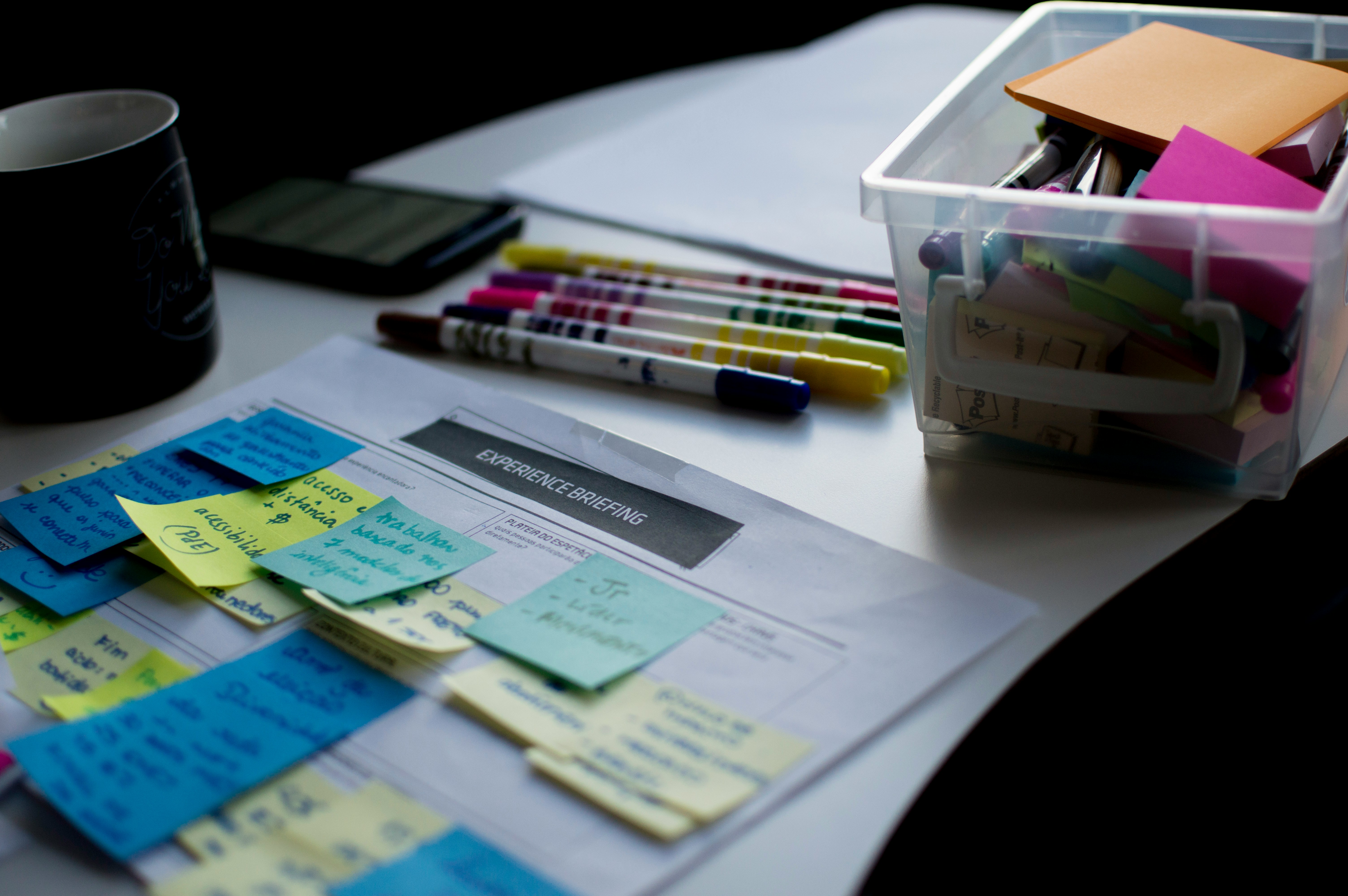 Creative workspace setup featuring an experience briefing document covered with handwritten sticky notes, surrounded by colorful markers, Post-it notes, and pens—ideal for UX design, agile sprint planning, or collaborative brainstorming sessions.